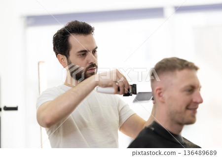 Professional barber cutting client's hair with clippers 136489689