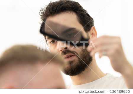 Barber carefully combing customer's hair at salon 136489690