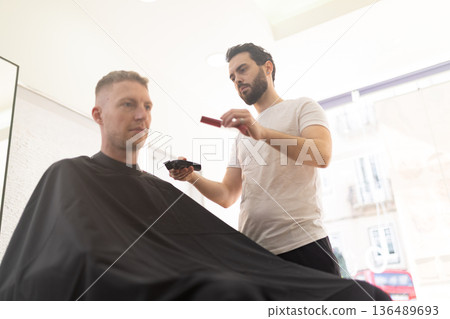 Barber giving a client a fresh haircut at salon 136489693