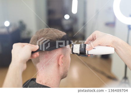 Barber giving client a fresh haircut in salon Barber giving client a fresh haircut in salon 136489704