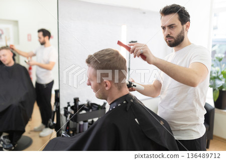Barber giving client a fresh haircut in shop Barber giving client a fresh haircut in shop 136489712
