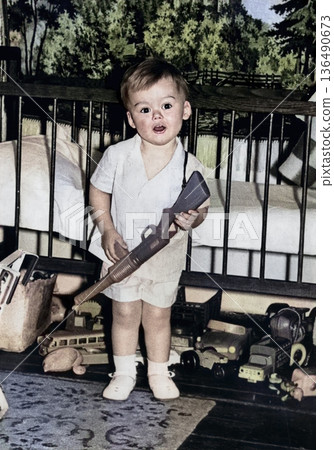 Vintage portrait of a little boy holding a toy machine gun. A funny photo of a cute boy and his toys. Retro photo, 1969. Vintage portrait of a little boy holding a toy machine gun. A funny photo of a cute boy and his toys. Retro photo, 1969. 136490673