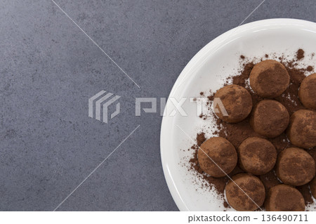 盤子裡的巧克力松露在灰色背景的襯托下格外醒目。 盤子裡的巧克力松露在灰色背景的襯托下格外醒目。 136490711