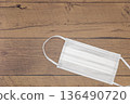 White nonwoven mask placed on a wooden table 136490720