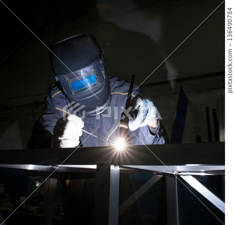 Welder working on metal structure in industrial workshop at night Welder working on metal structure in industrial workshop at night 136490784