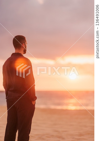 Young man watching sunset on beach contemplating life Young man watching sunset on beach contemplating life 136491006