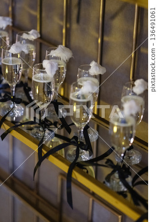 Champagne flutes topped with cotton candy on golden shelf with black ribbons 136491061