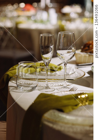 Empty wine glasses on table with green napkins in restaurant interior Empty wine glasses on table with green napkins in restaurant interior 136491066