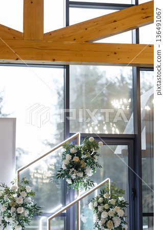 Wedding floral arch decor in banquet hall with wooden ceiling beams and large windows Wedding floral arch decor in banquet hall with wooden ceiling beams and large windows 136491067