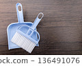 A mini broom and dustpan placed on a wood grain background 136491076