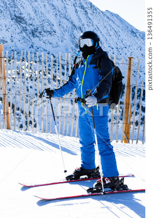 Young adult skiing in snowy mountain terrain with ski poles Young adult skiing in snowy mountain terrain with ski poles 136491355