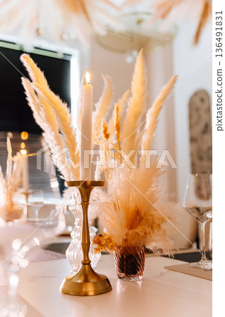 Elegant table setting with lit candle and pampas centerpiece Elegant table setting with lit candle and pampas centerpiece 136491831