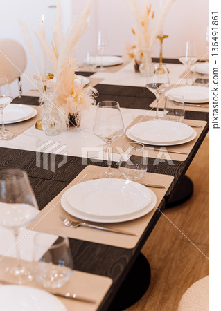 Elegant banquet table set with wine glasses, candles and pampas decor Elegant banquet table set with wine glasses, candles and pampas decor 136491861