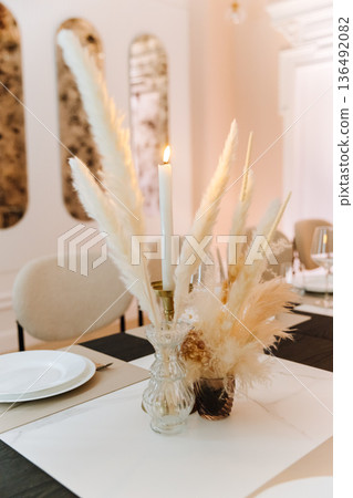 Boho candle centerpiece on elegant restaurant table with pampas grass Boho candle centerpiece on elegant restaurant table with pampas grass 136492082