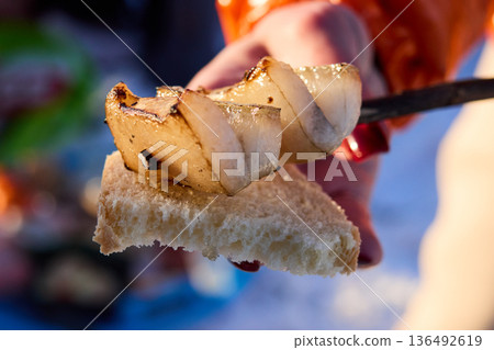 A hand holds grilled lard on bread, simple and tasty snack. A hand holds grilled lard on bread, simple and tasty snack. 136492619
