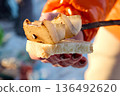 An alluring close-up of a person's hand holding bread with onion, showcasing a simple outdoor 136492620