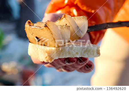 An alluring close-up of a person's hand holding bread with onion, showcasing a simple outdoor 136492620