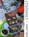 Preparing lard on a stick in a snowy outdoor setting with food on a green tray. 136492627