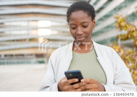 Young businesswoman using smartphone in front of Young businesswoman using smartphone in front of 136493470