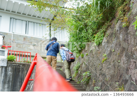 一名男子背對著鏡頭，正爬上有紅色扶手的樓梯。 136493666