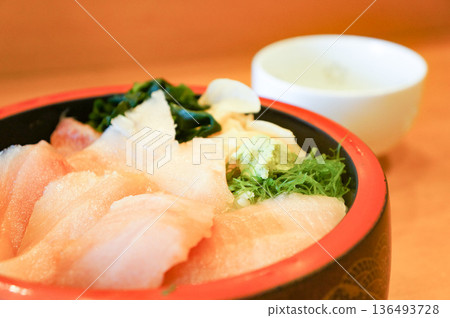 A bowl of rice topped with fresh seafood eaten in a tourist spot in a Japanese port town 136493728