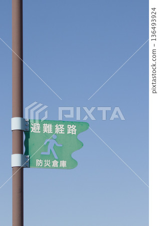 Evacuation route and disaster prevention storehouse signs against the backdrop of a clear blue sky 136493924