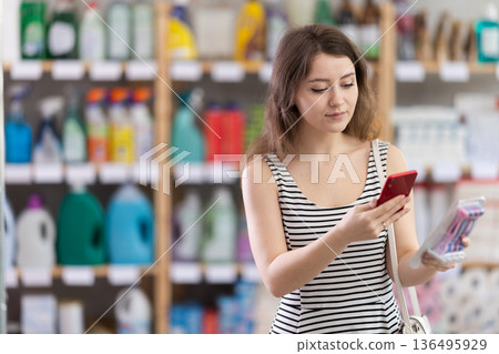 Female shopper scans QR code on label of razor for windows using smartphone 136495929