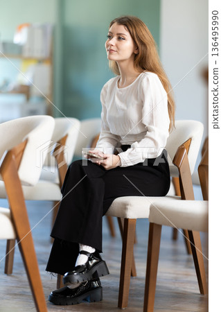 young woman receives additional education and holds a mobile phone in her hands 136495990