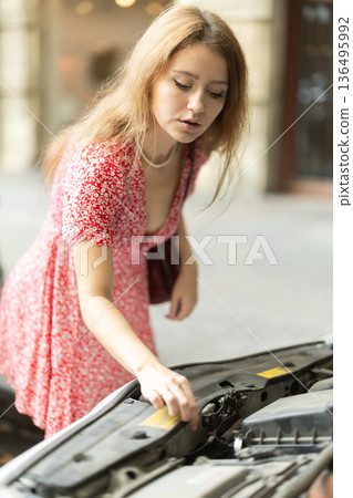 Young woman is worried about her car breaking down on city street 136495992