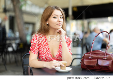 Young woman drinking coffee in glass mug 136495996