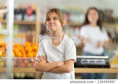 Portrait of capricious offended girl against background of dissatisfied mother - family quarrel in grocery store 136495997