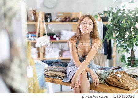 Sexy girl is sitting on table in sales area of store Sexy girl is sitting on table in sales area of store 136496026