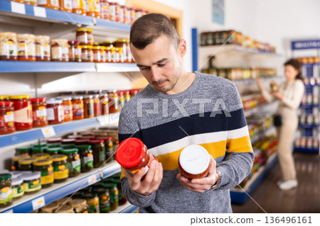 In Russian goods store, man choose jar of canned lecho In Russian goods store, man choose jar of canned lecho 136496161