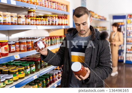 In Russian goods store, man choose jar of canned lecho In Russian goods store, man choose jar of canned lecho 136496165