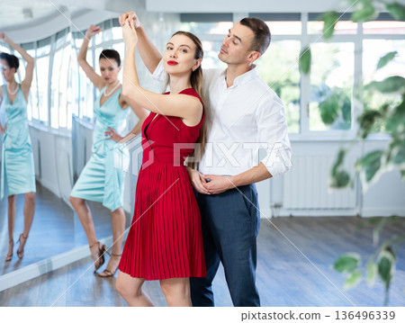 Couple in stage costumes learns boogie woogie dancing during individual lesson Couple in stage costumes learns boogie woogie dancing during individual lesson 136496339