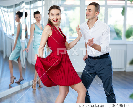 Couple in stage costumes learns boogie woogie dancing during individual lesson 136496364