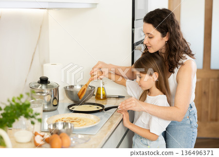 Mom and her daughter fry pancakes Mom and her daughter fry pancakes 136496371