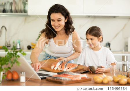 Happy mother and her daughter preparing salmon in the kitchen Happy mother and her daughter preparing salmon in the kitchen 136496384