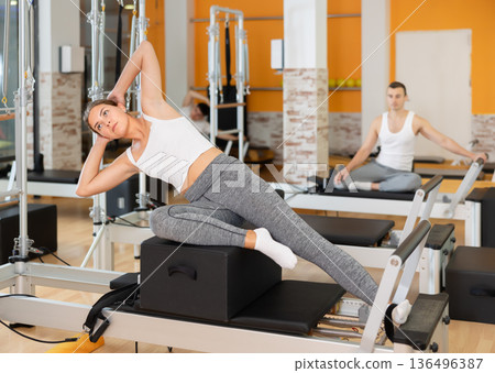Girl doing exercises on pilates reformer using sitting box 136496387