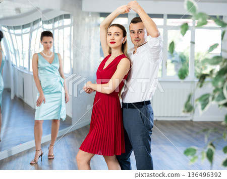 Man practicing samba with female partner in red in dance class Man practicing samba with female partner in red in dance class 136496392