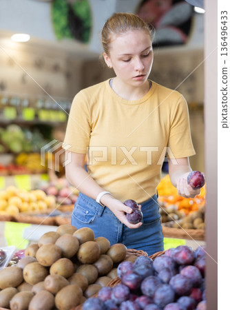 Teenage girl chooses plums in store Teenage girl chooses plums in store 136496433