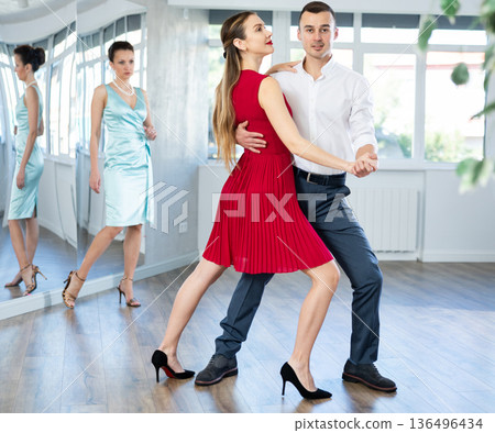 Graceful duet dancing passionate tango during dance class Graceful duet dancing passionate tango during dance class 136496434