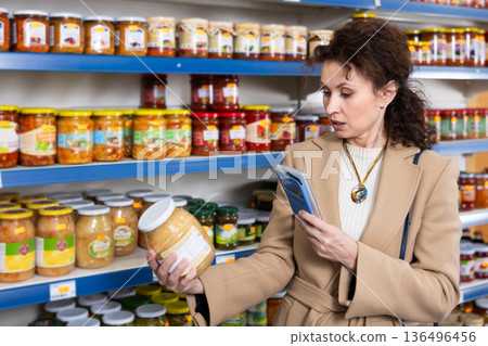 Female shopper scans barcode on jar of sauerkraut using a smartphone while shopping in grocery store Female shopper scans barcode on jar of sauerkraut using a smartphone while shopping in grocery store 136496456