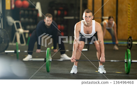 Man performing deadlift with barbell at group functional training 136496468