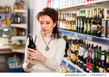 Adult woman choosing beer in store Adult woman choosing beer in store 136496472