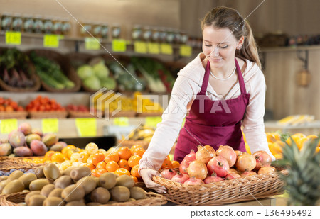 Female seller holding a basket of ripe pomegranates Female seller holding a basket of ripe pomegranates 136496492