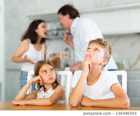 Brother and sister sit at table during quarrel between parents 136496503