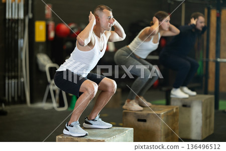 Man jumping up on box at functional cross training in gym Man jumping up on box at functional cross training in gym 136496512