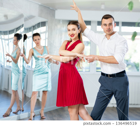 Couple in stage costumes learns waltz dancing during individual lesson Couple in stage costumes learns waltz dancing during individual lesson 136496519