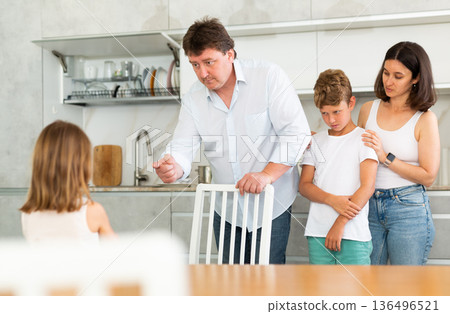 Little girl being scolded by angry parents and brother in the kitchen Little girl being scolded by angry parents and brother in the kitchen 136496521